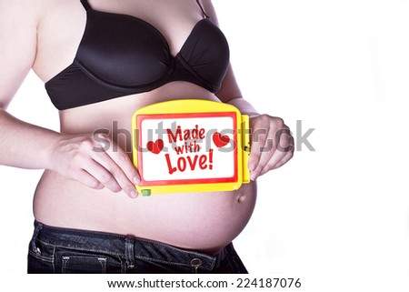 pregnant woman clothed in black bra and jeans holding a toy slate with text \