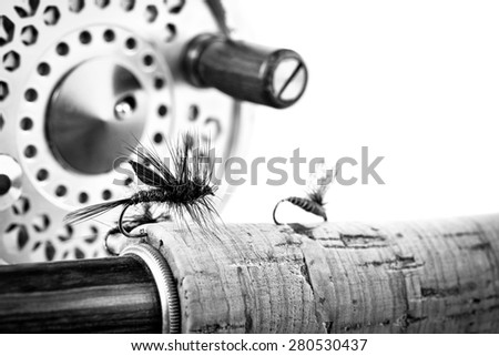 Black and White Close up of fly fishing lure, rod and reel on white background