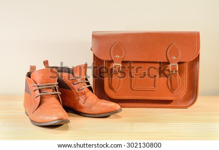 Still life with Brown leather shoes with leather bag on wooden table