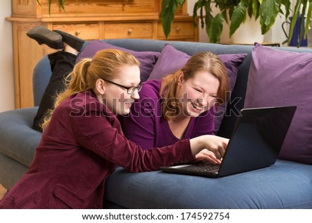 Two beautiful young women having fun with a laptop on the sofa