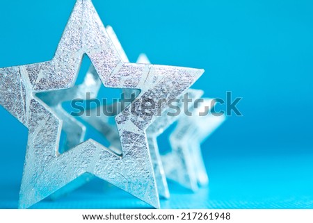 Shiny silver stars in different sizes on turquoise-blue background, copy space