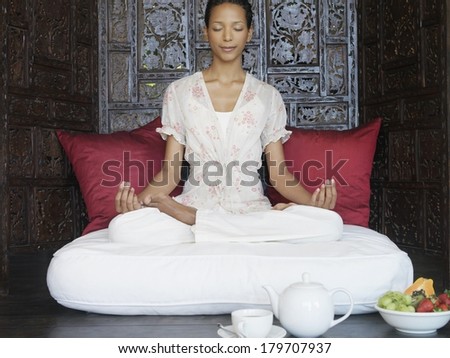 Beautiful black woman at spa meditating and practicing yoga