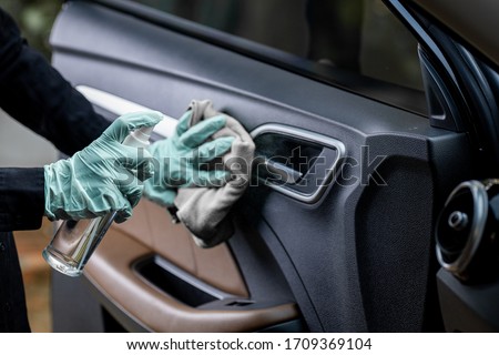Car disinfecting service. Woman disinfecting and cleaning the inside handle of the car door. Safety and preventing infection of Covid-19 virus, contamination of germs or bacteria, wipe clean surfaces
