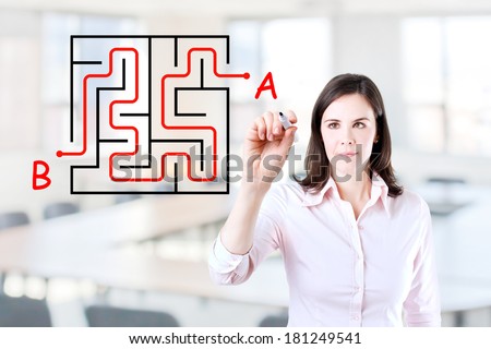 Young businesswoman finding the maze solution writing on the whiteboard. Office background.