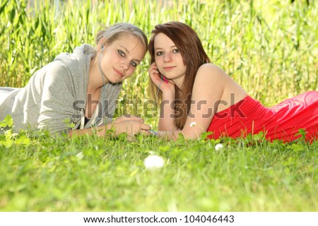young teenager girls sharing music on a meadow