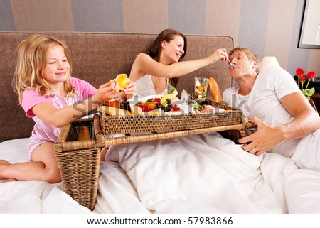 family having breakfast in bed - feeding each other