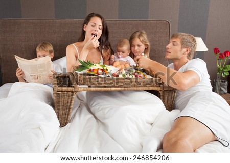 Family breakfast in bed - boy reading newspaper