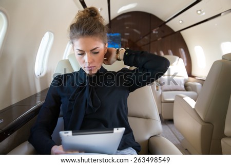 woman in corporate jet looking at tablet computer