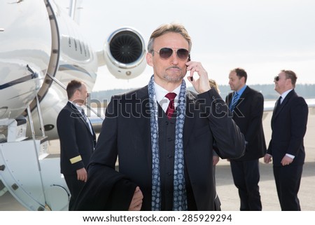 executive manager in front of corporate jet using a smartphone
