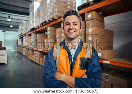 Smiling portrait of a male supervisor standing in warehouse with his arm crossed looking at camera Foto stock © 