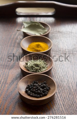 Dry herb served in wooden plate, rosemary, bay leaf, black pepper, turmeric