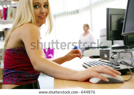 Photo of a pretty model at the library on a computer.