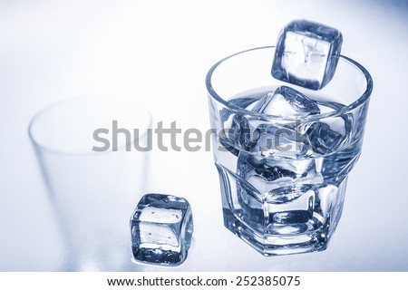 Ice cube falling into a glass of cold water.