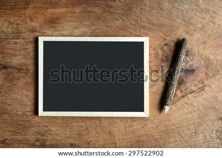 Blank blackboard and wooden pencil on old wooden background