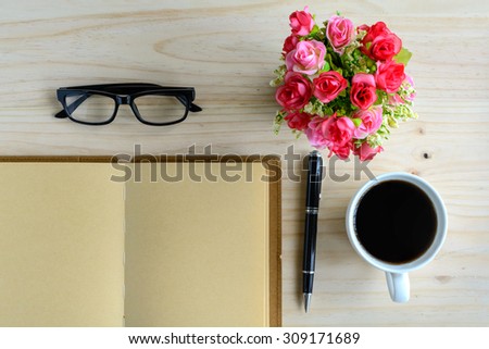 Cup of coffee with notebook and flower on desk, workplace