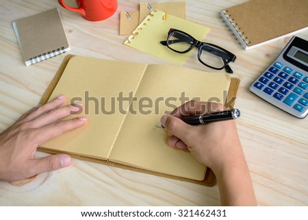 notebook with cup of coffee and office supply on desk with hand writing