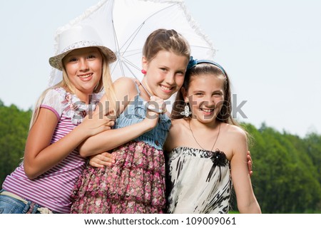 three happy young girl friends under umbrella
