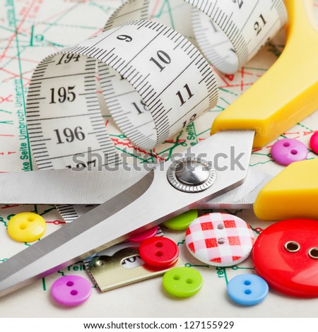 Sewing items: buttons, scissors, measuring tape  on sewing pattern