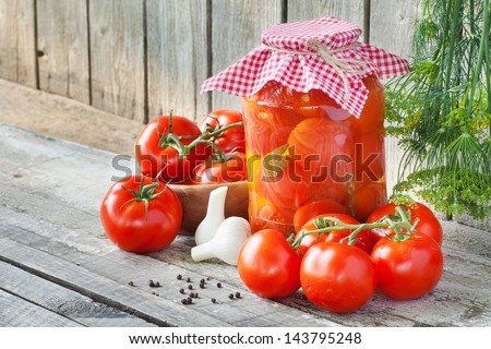 Homemade tomatoes preserves in glass jar. Fresh and canned tomatoes on wooden board