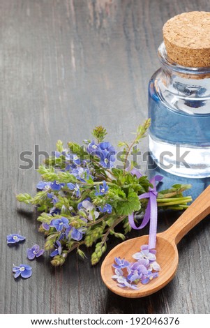 essential oil, wooden spoon and healing flowers on table
