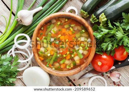 vegetable soup in wooden bowl and ingredients on wooden rustic table. top view