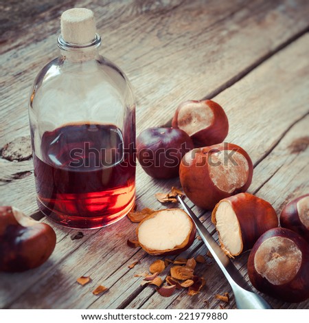 Chestnuts, knife and bottle with tincture on wooden table, herbal medicine