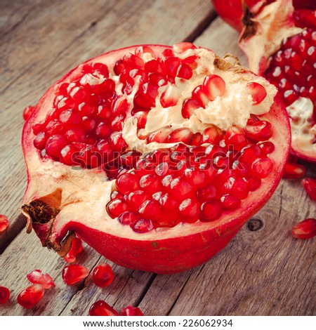 Piece of ripe pomegranate and red grains on wooden rustic table