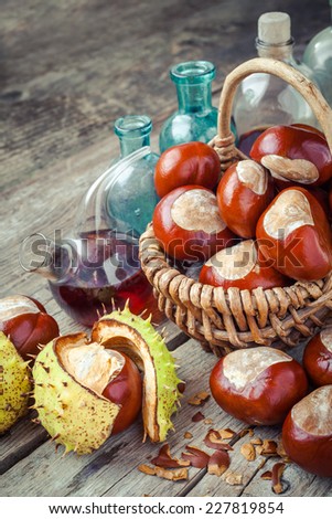 brown chestnuts in basket and vials with tincture on old wooden table