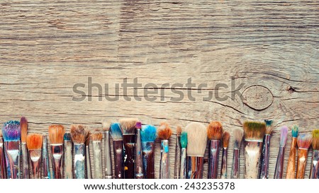 Row of artist paintbrushes closeup on old wooden rustic background