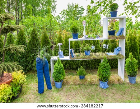 Minsk, Belarus, 23-May-2015: Garden composition -  bookshelf with books and potted plants, figure from jeans on holiday in nursery \