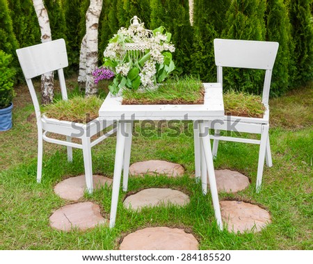 Minsk, Belarus, 23-May-2015: Garden composition -  table and chairs covered green grass, birdcage with lilac on holiday in nursery \