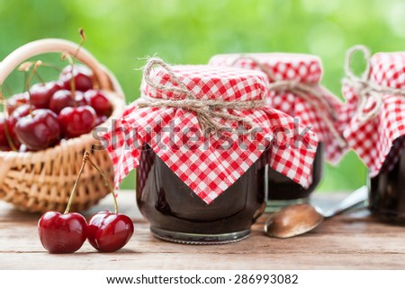 Jars of jam and basket with cherry.