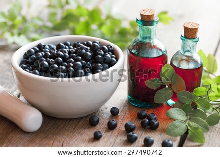 Mortar with blueberries and small bottles of tincture or cosmetic product.