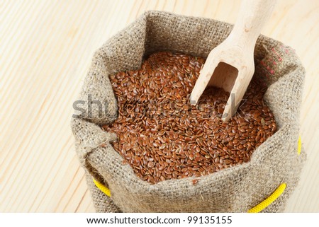 linseed, flax seeds with wooden scoop in sacking bag on wooden table