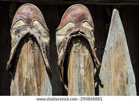 Torn vintage shoes without laces hanging on a wooden fence socks up.