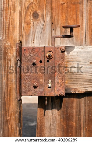 old rusty door lock on an ailing wooden gate