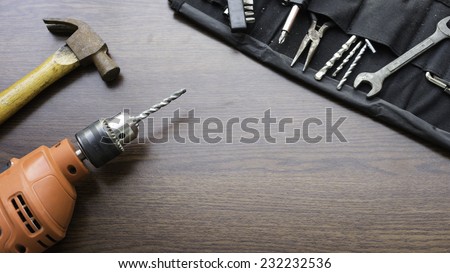 Concept of used power drill machine, hammer and some mechanic or carpentry tools kit on wooden board with room for text