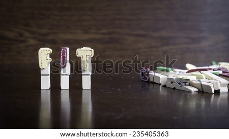 Common business terms - Slightly defocused and close-up of FIT word on clothes peg stick with lots of clothes peg at background