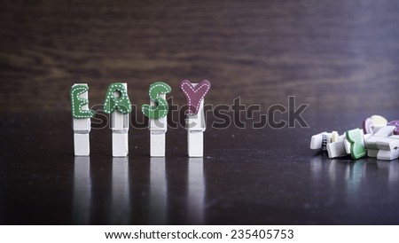 Common business terms - Slightly defocused and close-up of EASY word on clothes peg stick with lots of clothes peg at background
