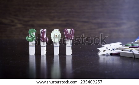 Common business terms - Slightly defocused and close-up of SLOW word on clothes peg stick with lots of clothes peg at background