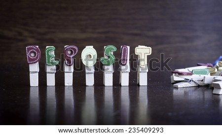 Common business terms - Slightly defocused and close-up of DEPOSIT word on clothes peg stick with lots of clothes peg at background