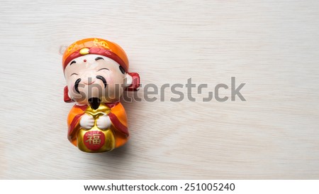 God of prosperity doll or Deity figurine holding a message 'Prosperity' and 'Money and Fortunes Come'. Concept of Chinese Lunar New Year. Slightly defocused and close-up shot. Copy space.