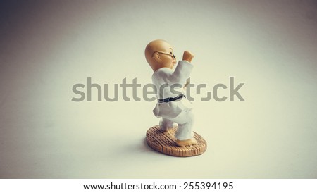 Retro color bald shaolin kungfu kid doll or martial art figurine. Concept of retro self-defence or asian martial art activities. Slightly defocused and close-up shot. Copy space.