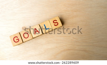 Block of alphabet letters forming the word GOALS on wooden surface. Concept of common marketing business terms. Slightly defocused and close-up shot. Copy space.