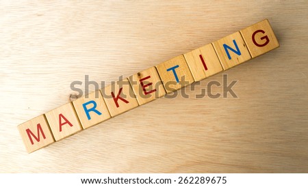 Block of alphabet letters forming the word MARKETING on wooden surface. Concept of common marketing business terms. Slightly defocused and close-up shot. Copy space.