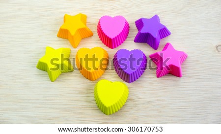 Silicone molds with starry and love shapes of different colors on a wooden surface. Concept of funky bakery or utensils for young chef. Slightly de-focused and close-up shot. Copy space.