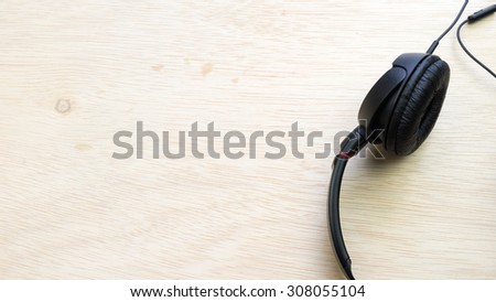 Black colour music headphones or headset gadget on wooden surface. Slightly de-focused and close-up shot. Copy space.