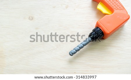 Orange and yellow color plastic drill machine and drill bit construction tool set on wooden surface. Concept of do it yourself education. Slightly de-focused and close-up shot. Copy space.