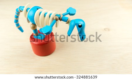 Cute blue colour wooden shape of dinosaur skeleton on red platform. Slightly de-focused and close-up shot. Copy space.