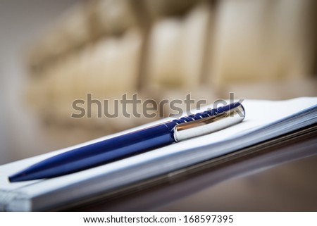 Closeup of notepad for agenda kept on table in empty corporate conference room before business meeting